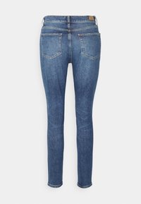 Jeans de denim azul ajustados con una cintura de talle medio, dos bolsillos traseros y un diseño simple y limpio con una tela texturizada.