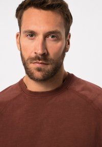 Bordeauxfarbener Sweatshirt mit rundem Halsausschnitt und Raglanärmeln. Weicher Stoff mit einer glatten Oberfläche und subtilen Farbvariationen.