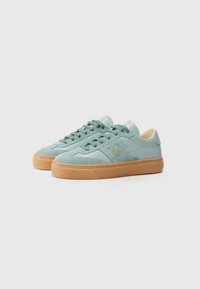 Mint green suede sneakers with a cream leather heel and tan rubber outsole. Features tonal laces and a gold logo accent on the side.