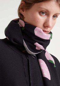 Bufanda negra con un patrón floral que presenta flores rosas y hojas verdes. Confeccionada en un tejido suave con acentos texturizados y un diseño sutil.