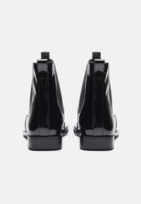 Black patent leather ankle boots with elastic side panels, a sleek design, and pull tabs at the back for easy wear.