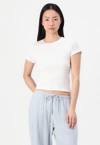 T-shirt blanc court à manches courtes, fabriqué dans un matériau doux. Associé à un pantalon de pyjama rayé bleu clair avec une taille à cordon.