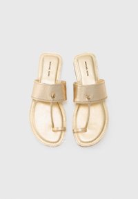 Kulta metalliset liukusandaalit, joissa on leveä hihna ja varvassilmukka. Luja pinta ja litteä pohja. Brändin nimi on painettu sisäpohjaan.