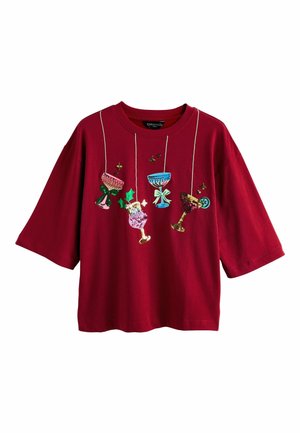 Red cotton t-shirt with short sleeves, featuring embroidered festive drink motifs and decorative strings, creating a playful holiday theme.