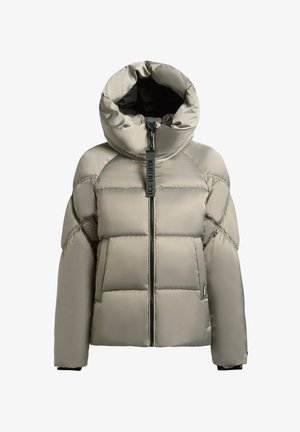 Vastag béléses pufi kabát világos bézs színben, magas gallérral és fekete cipzárral. Jellemzője a vízszintes steppelés és a logó címke részlet.