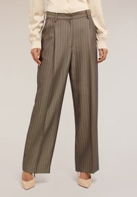 Hnědé kalhoty s jemným proužkem, vysokým pasem, širokými nohavicemi a předními záhyby. Tkanina vypadá hladce s jemným leskem.