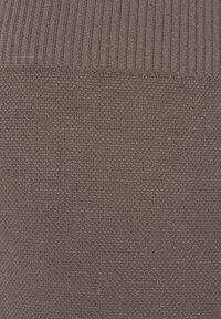 Bruine gebreide stof met een ribbeltextuur aan de bovenkant en een gladde, fijne weving eronder, wat een subtiel contrast in patronen creëert.