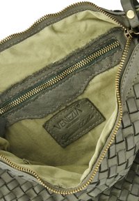 Green leather bag interior with woven texture, featuring a gold zipper, fabric lining, and a label reading "VENEZIA Genuine Leather."