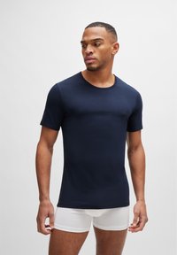 T-shirt in cotone blu navy con collo rotondo e maniche corte. Presenta un logo sottile sul petto. Tessuto liscio, design aderente.