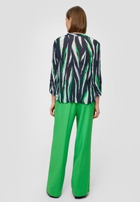 Õhuline blouse roheliste, mustade ja valgete triipudega, koos laiade roheliste pükstega. Pehme kangas ja mugav lõige.