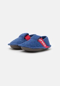 Ciabatta in felt blu con cinturino elastico rosso e logo "crocs". Texture morbida, forma rotonda e suola in gomma per uso interno.