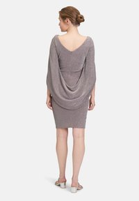 Robe grise étincelante avec une silhouette ajustée, des manches drapées et un dos en V profond. Texture lisse et design à mi-mollet. Sandales à talons argentées.