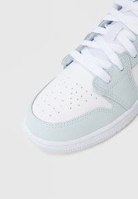 Jasnoniebieskie i białe sneakersy wykonane z gładkiej skórzanej materii, z perforowanym noskiem oraz białymi sznurowadłami. Podkreślone teksturowaną gumową podeszwą.