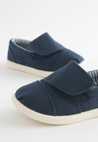 Navyblaue Stoffschuhe mit texturierter Oberfläche, ausgestattet mit einem Klettverschluss, weißer Gummisohle und gestreiftem Stofffutter.