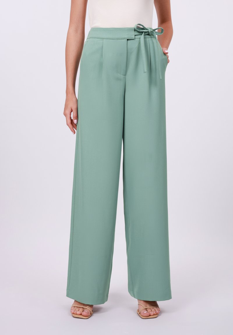 Light green wide-leg trousers with a fabric tie belt, pleated front, and side pockets. Smooth texture and full-length design.