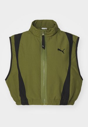 Kroppitud vest oliivrohelisest kangast mustade külgpaneelidega. Omab kõrget kaelust ja esimest lukku, millele lisab aktsenti logo vasakul küljel.