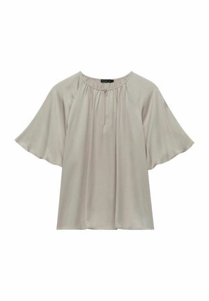 Ljus beige blus med rund halsringning, korta vågiga ärmar och mjukt, flödande tyg. Har samlad detaljering fram.