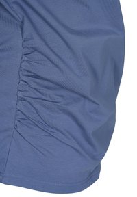 Blått tyg med mjuk textur, med ett samlat mönster på sidan. Sömmen är noggrant avslutad, vilket skapar en smidig silhuett.