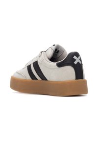 Zapatillas con una parte superior de ante gris, rayas negras y suela de goma. Presenta un cuello acolchado y un sutil detalle del logo en la lengüeta.