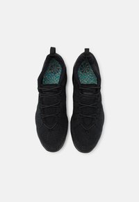 Black athletic shoes with a textured, knitted upper and lacing system. Inside features a multicolored patterned insole.