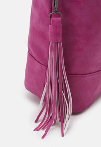 Fioletowa torebka z zamszu z długim frędzlem w różowe i białe pasy oraz haftowanym brzegiem na dole dla dodatkowej tekstury.