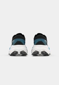 Black and blue athletic shoes with a textured upper, white midsole, and black tread pattern on the outsole. Reflective accents visible.