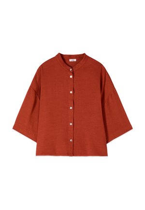 Blouse ample couleur rouille avec manches trois-quarts, col rond et rangée de boutons blancs sur le devant au centre.