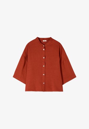 Blouse in roestkleur, losse pasvorm, met driekwart mouwen, ronde kraag en een rij witte knopen aan de voorkant in het midden.