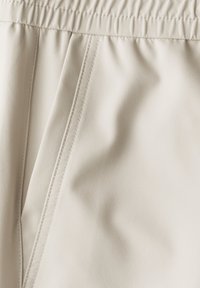 Beige shorts met een elastische tailleband, gemaakt van een gladde, gestructureerde stof met stikdetails en zachte draping.