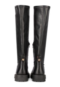 Black leather knee-high boots with a smooth finish, back zippers, and textured heel accents. Features round emblem on the back.