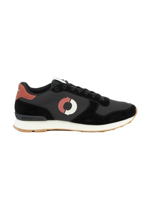 Zapatilla negra y gris oscuro con lengüeta roja en el talón, logo circular de flecha blanca y roja en el lateral, cordones negros, suela blanca y suela exterior de goma.