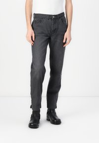 Jeans dritti grigi scuri in denim con una leggera sfumatura, dotati di tasche frontali e chiusura con bottone, abbinati a stivaletti neri alla caviglia.