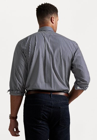Ανδρικό πουκάμισο με ναυτικές και λευκές ρίγες και κολάρο με κουμπί. Με διπλωμένα μανίκια και ίσια πλάτη. Συνδυάζεται με σκούρο τζιν.