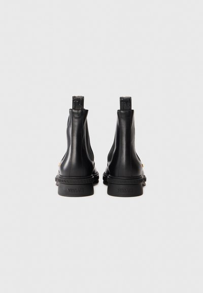 Botine din piele neagră până la gleznă, cu manșete, model embossat cu motivul cheie grecesc pe tocuri și marca "Versace" pe marginile talpilor.