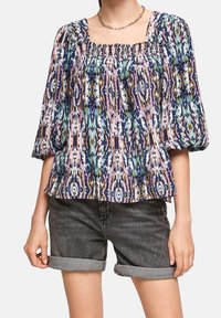 Flerfärgad blus med fyrkantig halsringning, puffärmar och samlad detaljer; har ett livligt abstrakt mönster på en ljus bakgrund.