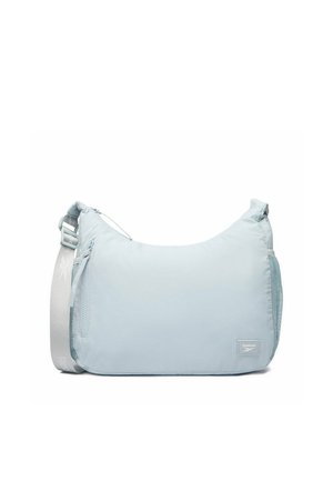 Jasnoniebieska torba na ramię Reebok z regulowanym paskiem, przednią kieszenią na zamek i siateczkową boczną kieszenią na białym tle.