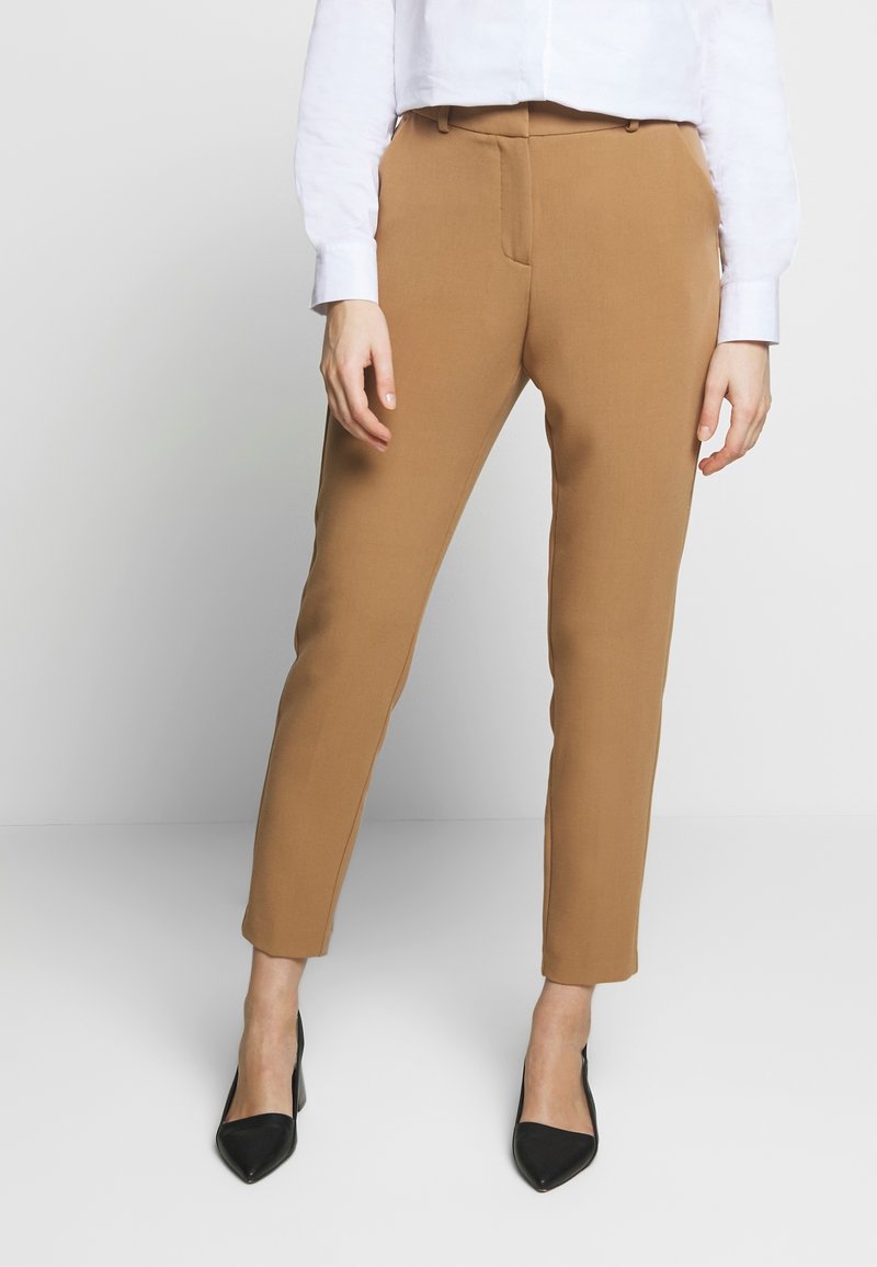 Bruna skräddarsydda byxor med smal passform, som har en mjuk yta, två framfickor och midjehight på medelhöjd, tillsammans med svarta spetsiga klackar.