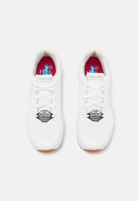 Zapatillas blancas con secciones perforadas, cuello acolchado y suela antideslizante. Cuenta con una plantilla de espuma viscoelástica y acentos de logo en la lengüeta.