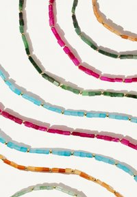Des colliers en perles colorées avec des perles rectangulaires en rose, vert, bleu et orange, entrecoupés d'espacers dorés, sur un fond blanc.