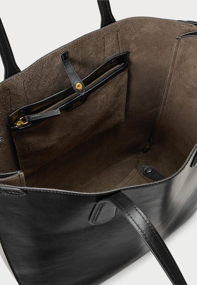 Μαύρη δερμάτινη τσάντα tote, με σουέτ εσωτερικό, τσέπη με φερμουάρ και απαλό υφή. Ο σχεδιασμός περιλαμβάνει διπλούς χειρολαβές και οργανωτικά διαμερίσματα.