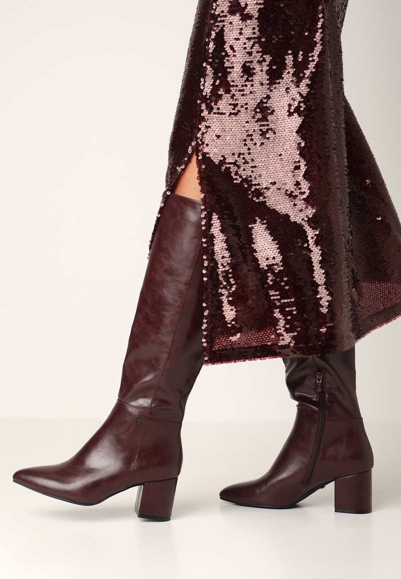 Burgundské kozačky ke kolenům vyrobené z lesklé kůže s blokovým podpatkem, se zapínáním na zip na boku a minimálním detailem šití.