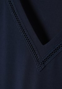 Haut en tissu bleu marine avec un décolleté en V et une délicate bordure en dentelle le long des bords, texture lisse et éléments de design minimaux.