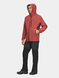 Czerwona wodoodporna kurtka z kapturem, z zamkiem błyskawicznym z przodu i kieszeniami, w połączeniu z czarnymi spodniami i solidnymi czarnymi butami. Stworzona z myślą o aktywności na świeżym powietrzu.