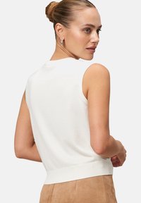 Haut sans manches blanc avec un ourlet côtelé, fabriqué à partir d'un matériau tricoté doux, présentant un col rond et une coupe ajustée.