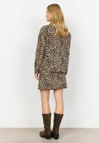 Leopard print long-sleeve shirt and skirt set, featuring a soft fabric texture, a relaxed fit, and paired with brown knee-high boots.