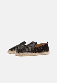Scarpe slip-on in pelle intrecciata nera con un design testurizzato, dotate di una suola in corda di juta. Fodera interna liscia e punta arrotondata.