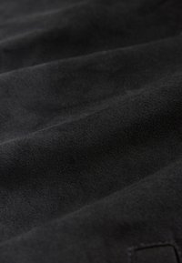 Gros plan sur un tissu en daim noir doux montrant une texture fine et des plis délicats.