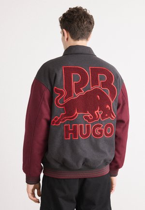 Gray and burgundy bomber jacket featuring large red embroidered 'RB HUGO' logo and bull design on the back, with ribbed cuffs and hem.