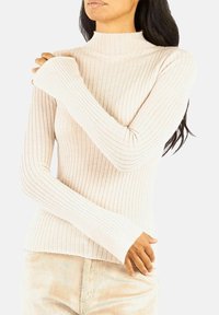 Maglione a collo alto a maniche lunghe con coste color beige chiaro, dalla silhouette aderente e maniche allungate, realizzato in un morbido tessuto a maglia.