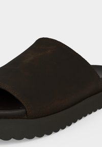 Sandale à enfiler en cuir brun foncé avec une large bride et une semelle épaisse noire striée pour un usage décontracté.